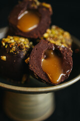 A still life of chocolate truffles with liquid filling at dark background