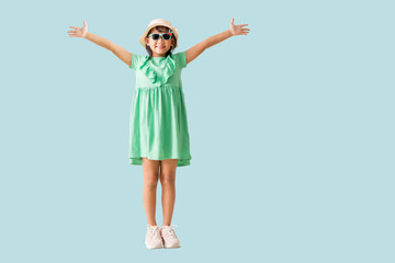 Happy smiling asian little girl were hat and sunglasses radiating happiness and freedom, Full body isolated on blue background