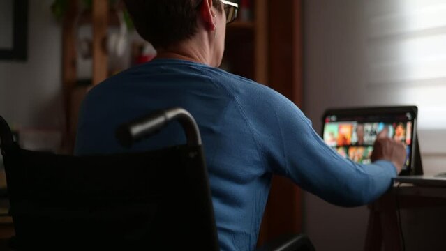 Woman With Disability In A Wheelchair Enjoying Streaming Services At Home Using A Digital Tablet. Home Entertainment For People With Physical Disabilities.