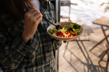 Cropped shot of unrecognizable healthy young woman holding salad bowl and eat clean vegetables for...