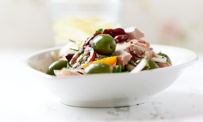 Salad with tuna, green olives and cherry tomatoes. Bright wooden background. Close up. Copy space.
