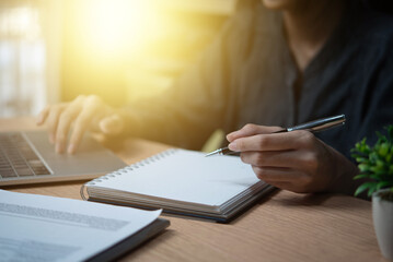 Female hand holding a pen to write goals or take diary notes on the desk