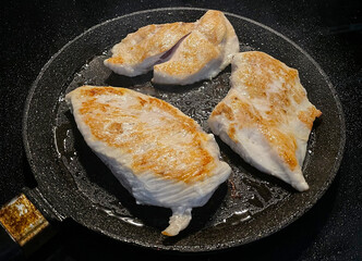 The process of cooking chicken steak in a frying pan in close-up, top view. Golden crust of baked chicken breast, healthy food. Frying chicken at home. Fried chicken fillet.