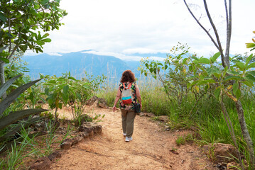 Unrecognizable woman seen from the back walking in a natural area near Barichara, the most...