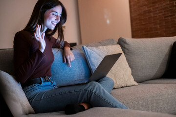 Happy brunette girl waving hand using laptop app enjoying online virtual chat video call in remote...