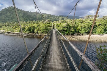 Fototapeta premium Hiking trail bridge crossing the Kohaihai River on Heaphy Track, Karamea, West Coast, New Zealand.