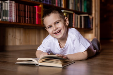 little boy is reading a book in the library at home