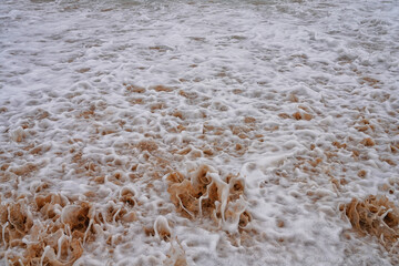 Aufschäumendes Wasser der Brandung mit Sand versetzt