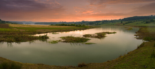 A light rain falls on the lake at sunrise. Quiet view of the lake on a beautiful morning