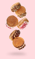 Delicious round croissants in air on pink background. Puff pastry