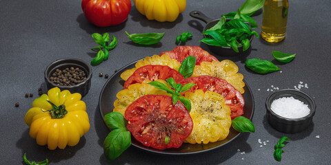 Colorful Heirloom tomato harvest. Ripe ribbed vegetables with fresh basil leaves. Wooden background