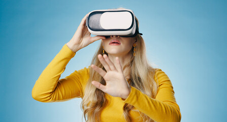 VR, woman and hand in studio for metaverse, digital and video game on blue background. Technology,...