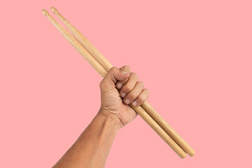 Black male hand holding wooden Drum sticks isolated on pink background