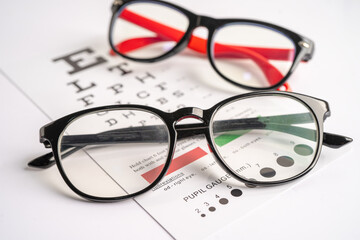Glasses on eye testing exam chart to check eyesight accuracy of reading.