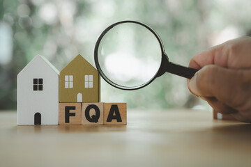 Man hand uses magnifying glass to find answer FAQ about home. The concept of FAQ about house...