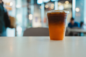 Ice coffee, americano coffee with orange on table in cafe.