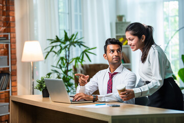 Fototapeta premium Indian asian young CEO businessman working with female colleague in the office using laptop computer