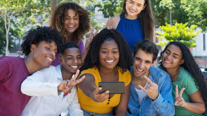 Laughing latin american and hispanic and african american and caucasian young adults taking selfie...
