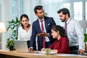 Indian young businesspeople using laptop in group meeting at desk