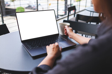 Mockup image of a woman working on laptop computer with blank white desktop screen while drinking...