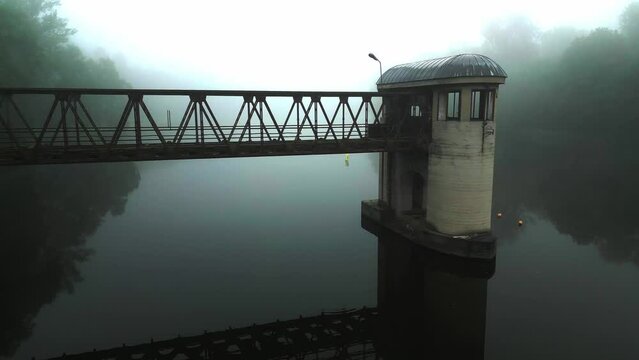 A hazy scene with an abandoned lock over calm water.