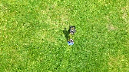 Gardener cuts the lawn. Mowing lawns. Aerial view garden man lawn mower on green grass. Mower grass equipment. Mowing gardener care work tool. Aerial lawn mowing