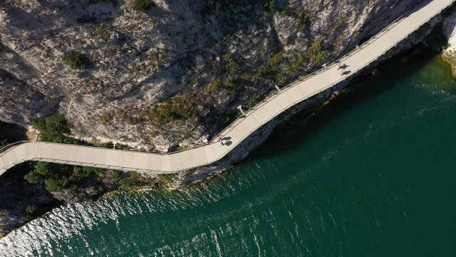 Garda bike path. Bicycle/pedestrian path Garda suspended above the lake. Alley of Limone sul Garda. Section of the longest cycle path in Europe 4K aerial view.