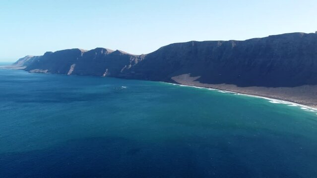 High altitude aerial drone view of Lanzarote island part of Canary Islands Spain showing the rough mountain coast first and in far background La Graciosa a smaller isle 4k resolution quality