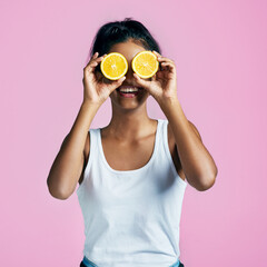 Girl, eyes and funny with orange slices as gen z on pink background for fashion, style and energy. Female person, happiness and citrus fruit in playful, aesthetic or creativity in studio backdrop