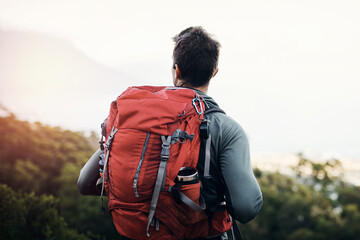 Hiker, backpack and nature for adventure, outdoor and person in mountains, fitness and sports of climbing. Sightseeing, healthy and man with supplies in bag, back and explore in forest and active