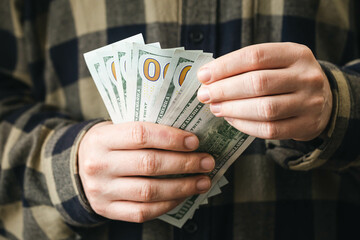 Close up, one hundred dollar bills in male hands, finance and budget.