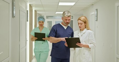 Medical professionals reviewing patient information on clipboards in a hospital hallway, displaying teamwork and dedication to healthcare. Medical Team Discussing Patient Records