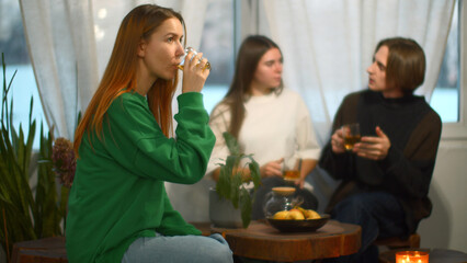 Students talk and relax in cozy cafe. Media. Beautiful young woman is drinking tea on background of...