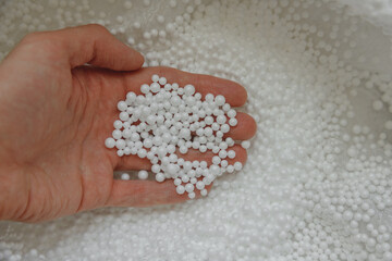 Polystyrene balls in hand. Packaging of fragile goods, filling for chair bags and pillows