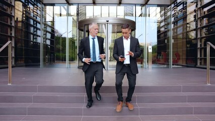 Two caucasian business colleagues talking happily, co-workers talking walking around the city outdoors, say goodbye together after work