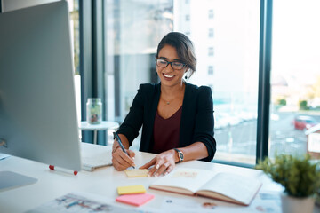 Business woman, computer and happy in office for work, schedule and planning with notebook. Project manager, technology and smile in workplace for kpi, administration and company goals with research
