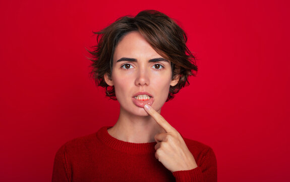 Close-up portrait of gum inflammation. A cropped shot of a young woman showing red bleeding gums isolated on a bright red background. Dentistry, dental care.