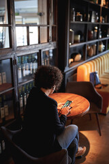 back view of a woman looking the mobile phone in the hotel lobby.