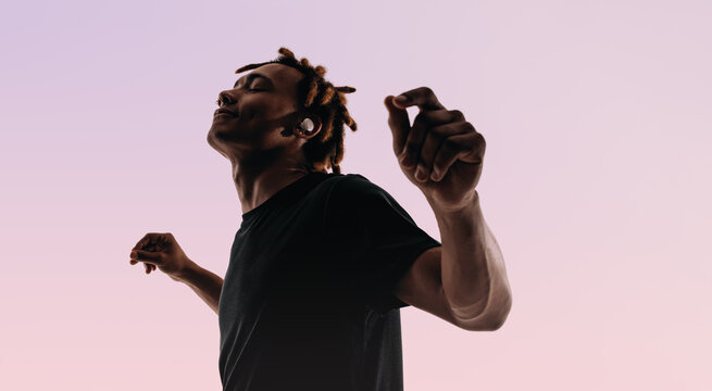 Vibrant dance moves of a young man in silhouette against a pink background