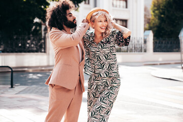 Beautiful fashion woman and her handsome elegant boyfriend in beige suit. Sexy blond model in summer suit clothes. Fashionable smiling couple posing in street Europe. Brutal man and female outdoors