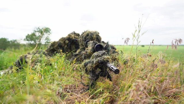 Close-up portrait of a military sniper in camouflage green army clothes. sniper in camouflage suit looking at the target. 4k video.