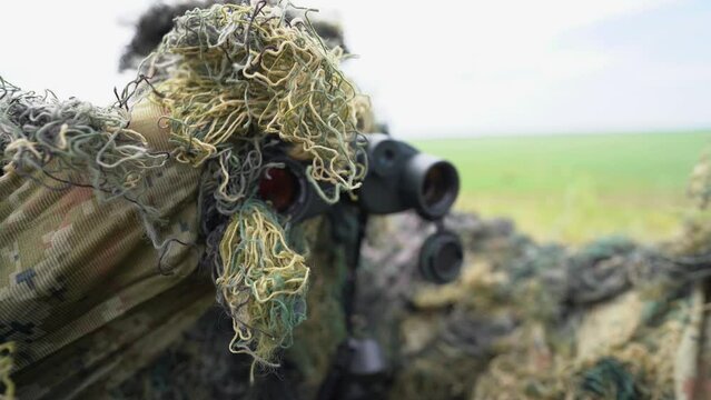 Close-up portrait of a military sniper in camouflage green army clothes. sniper in camouflage suit looking at the target. 4k video.
