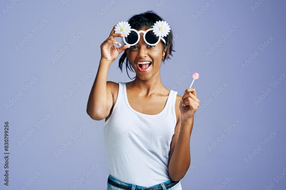 Sticker Girl, lollipop and happy with sunglasses in studio on purple background in casual, style and elegant. Portrait, fashion and excited with smile for clothes or street wear, outfit and confident