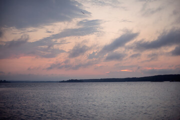 Sunset over the river with a line of trees in the background in summer and sun rays
