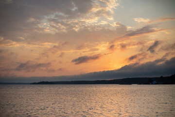 Sunset over the river with a line of trees in the background in summer and sun rays
