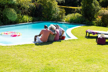 Outdoors, diverse senior friends relaxing by pool, enjoying sunshine