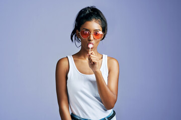 Portrait, sunglasses and woman with lollipop in studio for fashion eyewear, designer brand or...