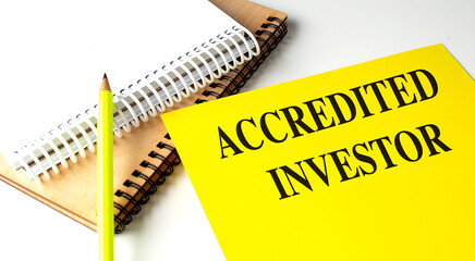 ACCREDITED INVESTOR text on yellow paper with notebooks