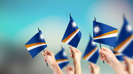 A group of people are holding small flags of Marshall Islands in their hands.