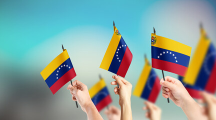 A group of people are holding small flags of Venezuela in their hands.